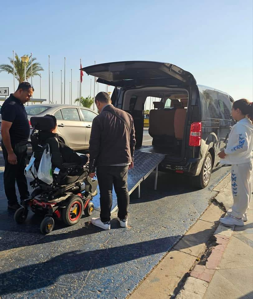 Professional driver assisting wheelchair passenger into vehicle
